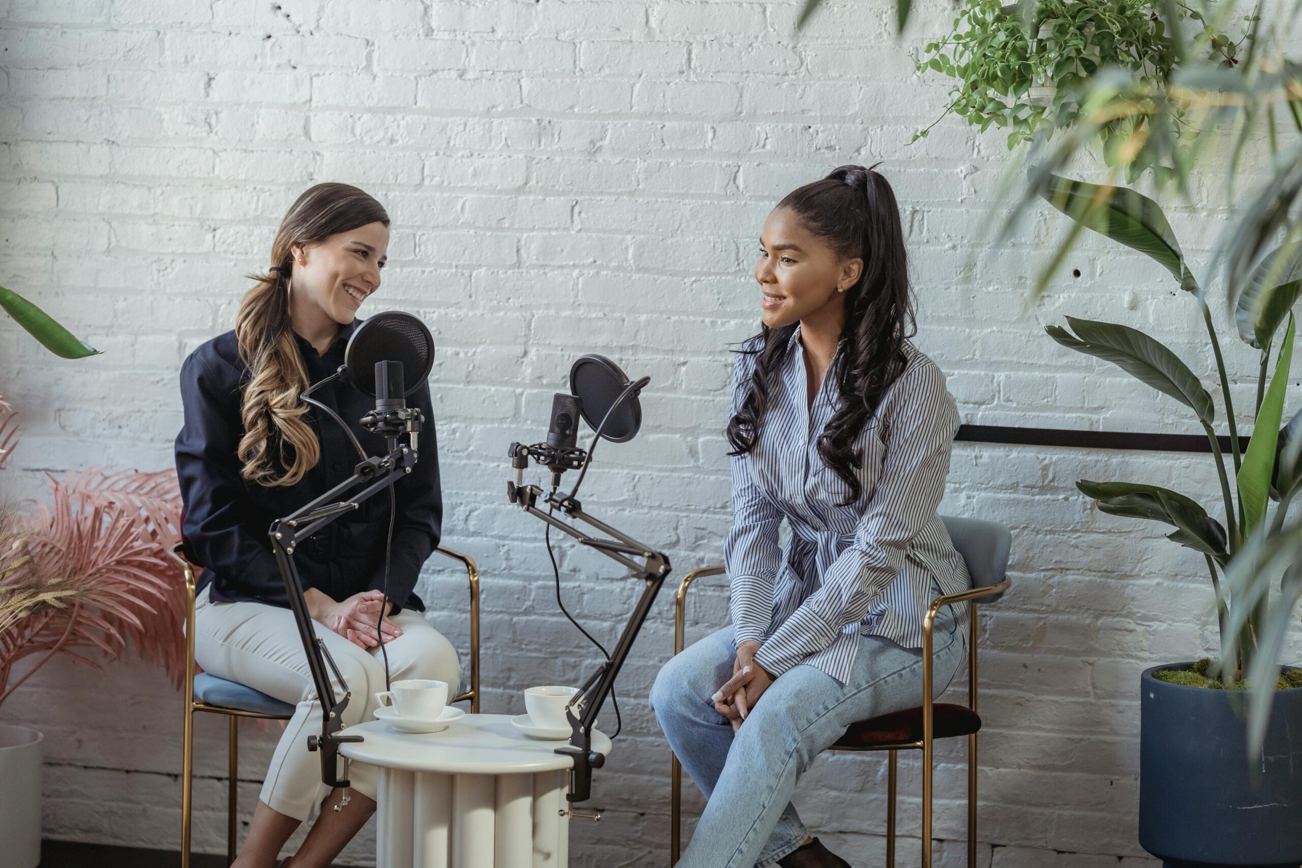 Home Diverse women communicating while recording voice in studio with white brick walls in daytime