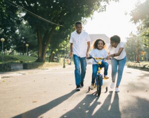 Podcast Happy family teaching their child to cycle on a sunny day outdoors.