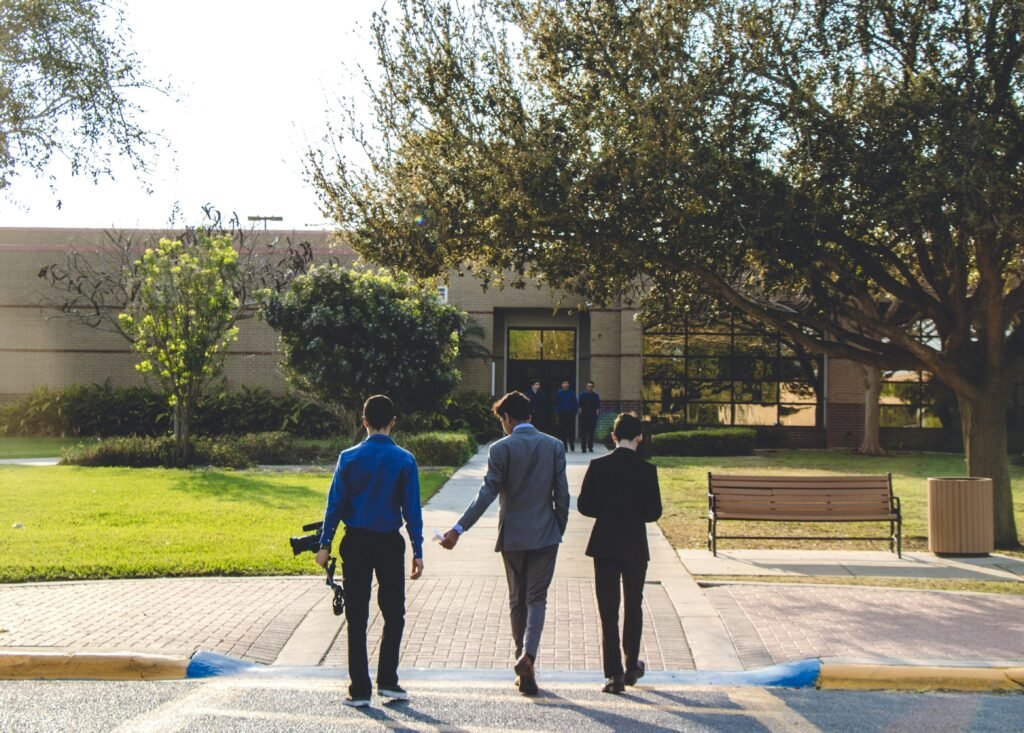 Three adults walking towards a building in Mercedes, Texas, surrounded by trees and greenery.