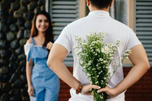 Podcast A man surprises his partner with flowers behind his back, symbolizing love and romance.